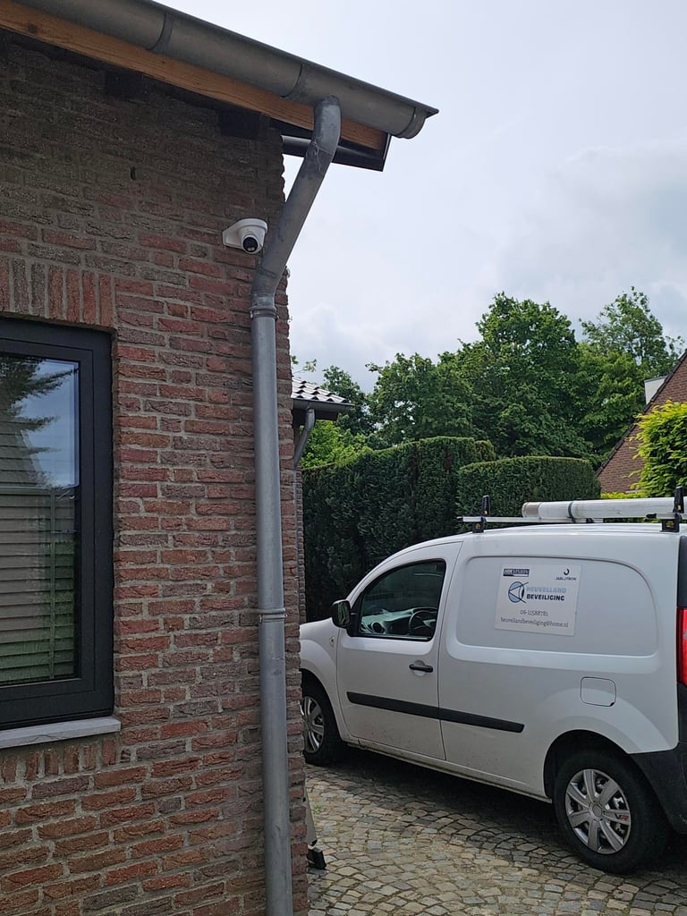 White service van parked in front of brick house with security camera mounted on wall